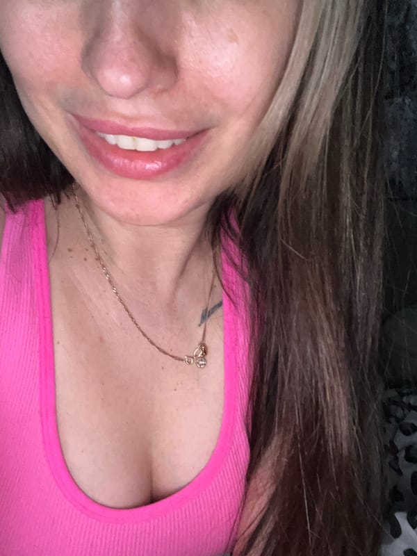 Woman takes casual selfies in pink top on patterned bedding