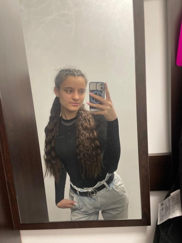 Young woman takes mirror selfie in black top