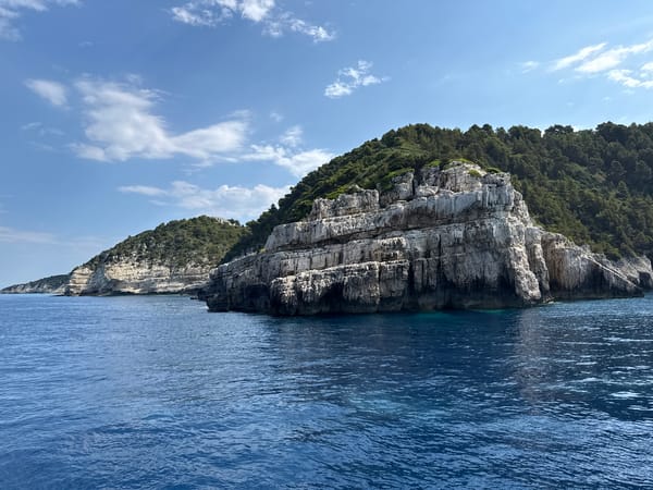 Rocky Greek coastline where green cliffs meet sapphire sea