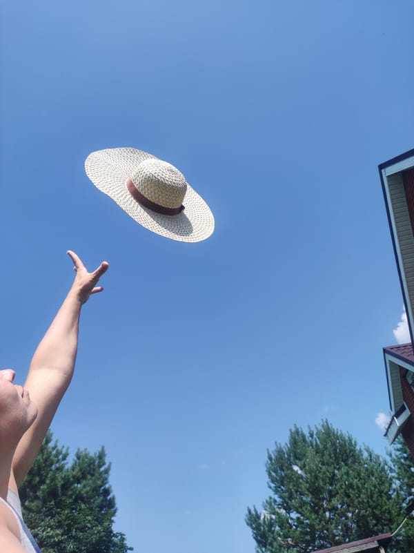 Backyard summer day: poodle, a straw hat toss, and blue skies