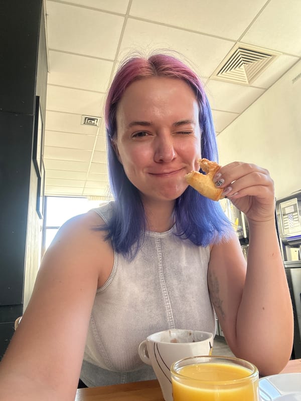 Colorful-haired woman enjoys breakfast at French cafe