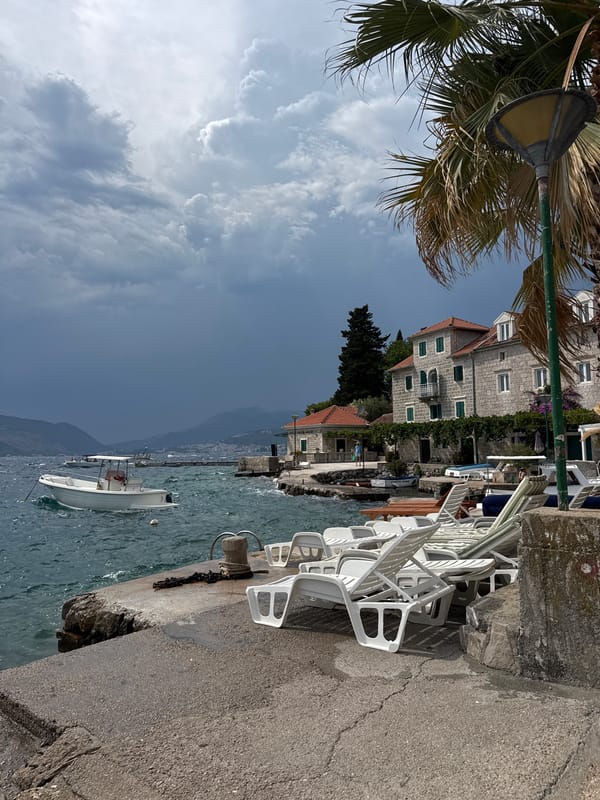 Choppy waterfront, moored boats, and stone buildings midday