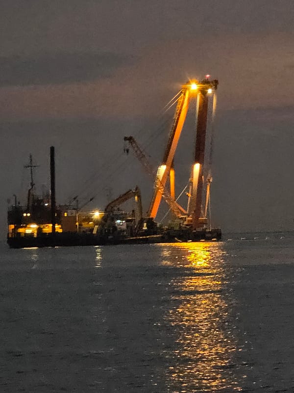 Dusk hits the Dierhagen coast alongside a lit construction barge