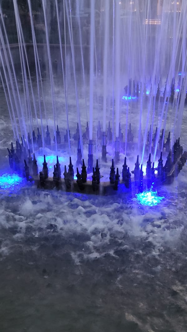 Urban park at dusk: fountains, monuments, and street life