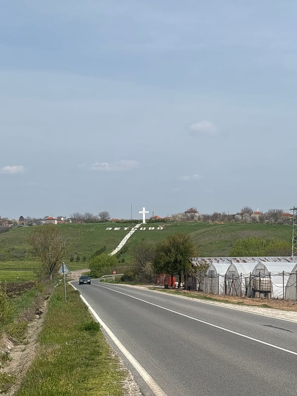 White cross stands in field alongside road in Zetiovo
