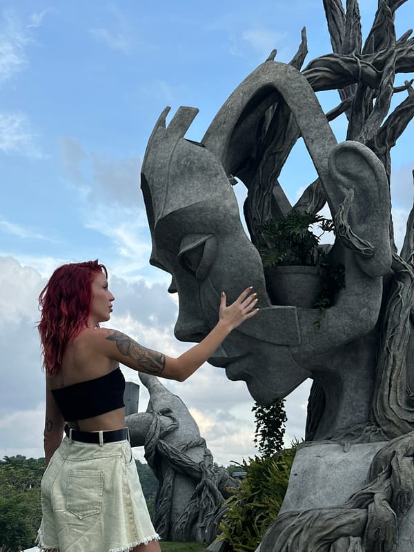 Visitors pose with monumental head sculpture in Kediri park
