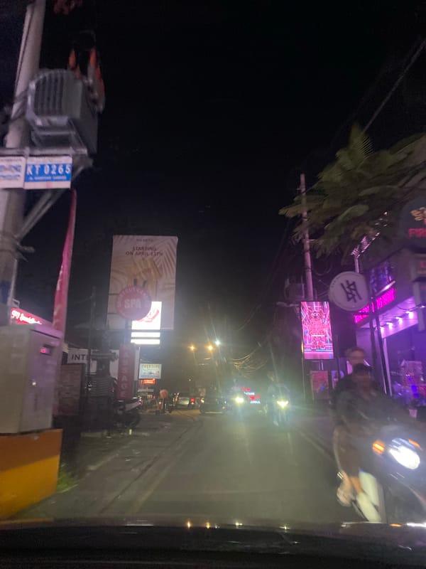 Evening drive through illuminated North Kuta commercial district captured