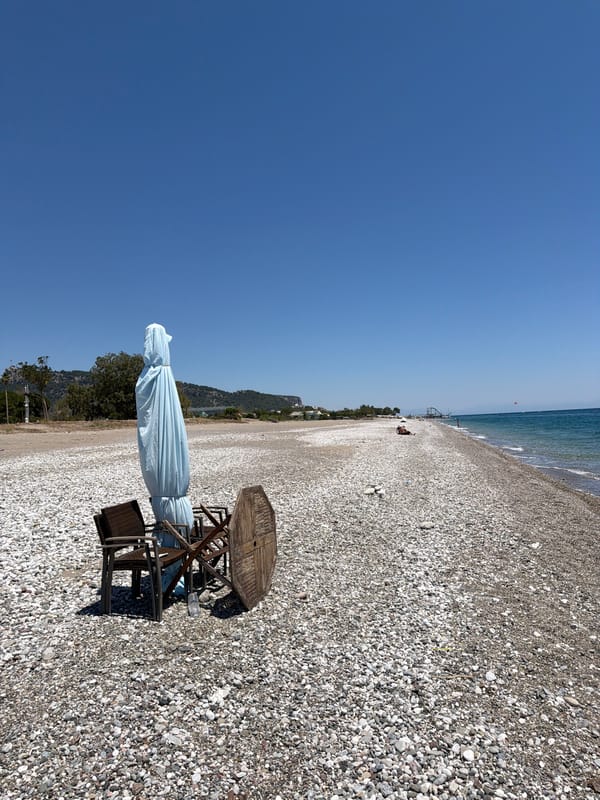 Busy pebble beach resort with water sports and a Neptune statue