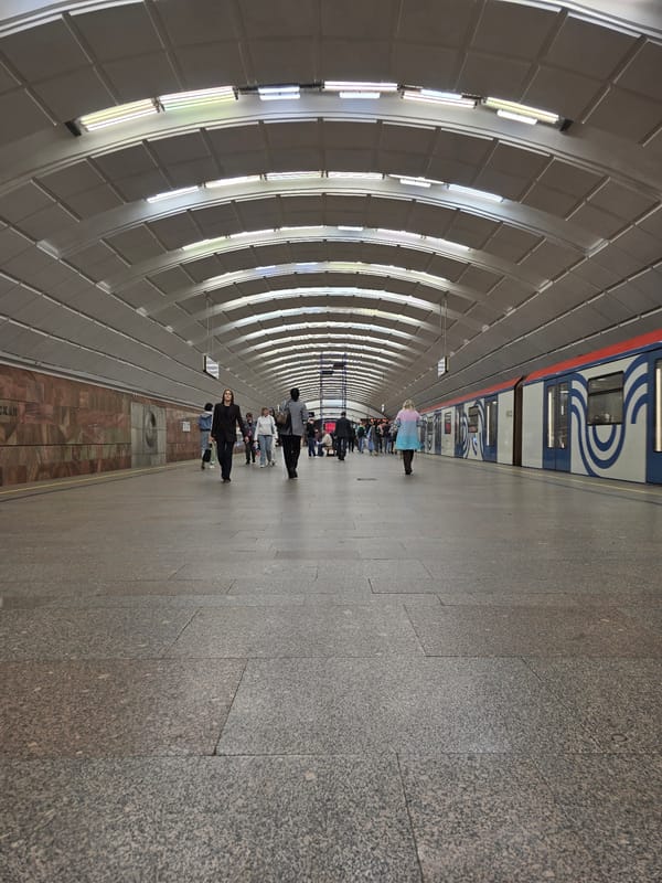 Subway train arrives at station platform displaying Cyrillic destination