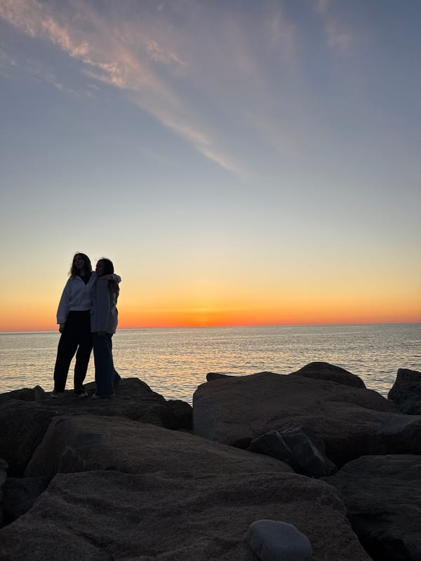 Two women stand on coastal rocks in Batumi