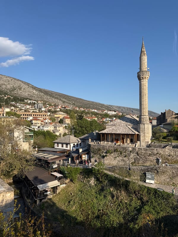 Stone minaret stands tall against blue skies in Mostar
