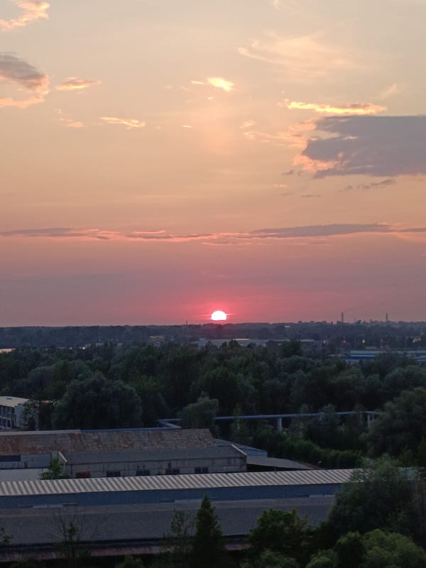 Warm sunset light fades over Riga's industrial skyline