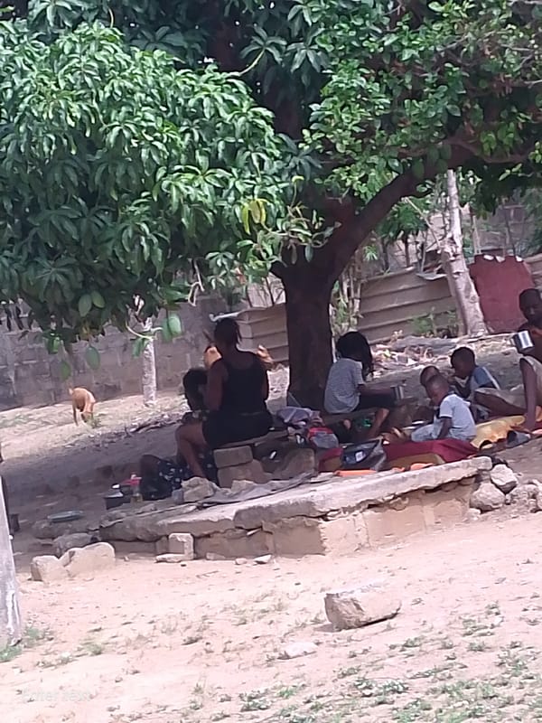 Community gathering under tree, teal sedan parked nearby