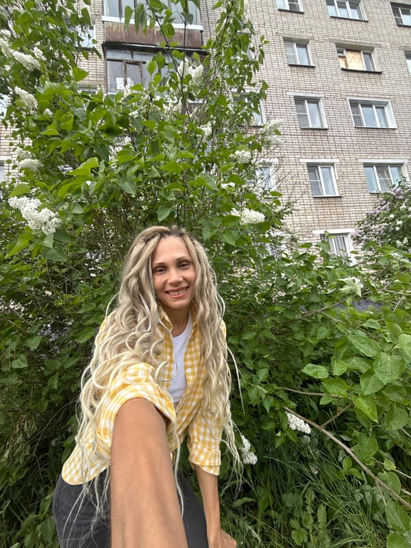 Woman poses among lilac flowers in Russian village morning