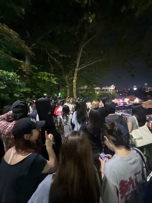 Nighttime crowd gathers in Seoul with mixed seating arrangements