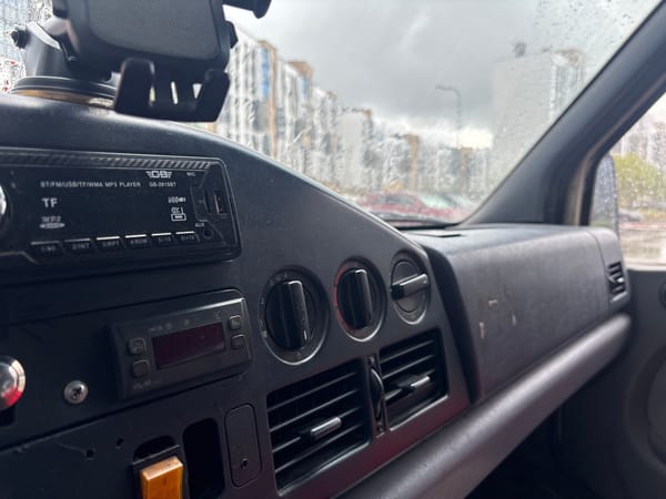 Rainy city drive past modern buildings and a parked delivery van