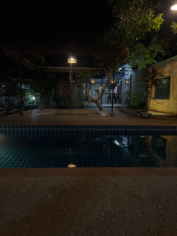Relaxed nighttime hangout at a poolside thatched-roof retreat