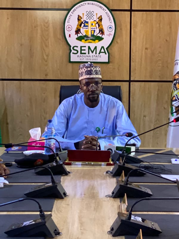 Man in traditional attire observed at indoor meeting