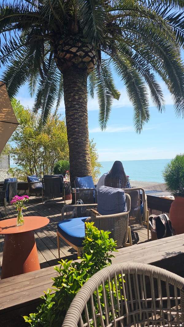 Woman enjoys coffee and cake at Gagra beachside cafe