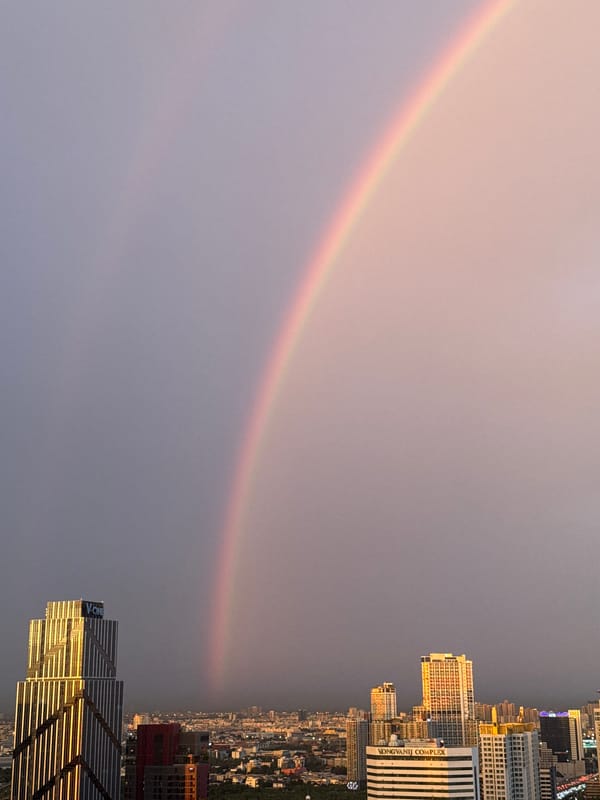 Bangkok skyline under stormy skies with rainbows, June 2026