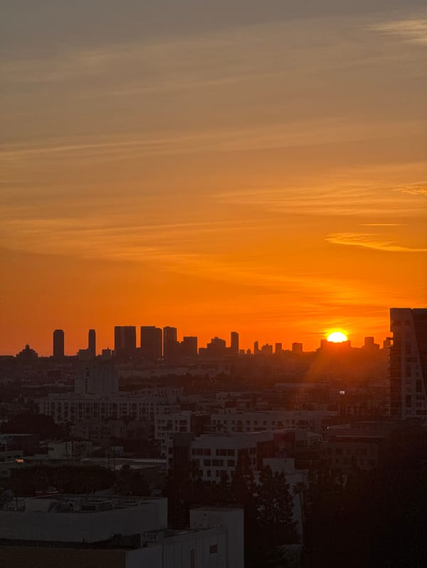 Orange sunset illuminates Los Angeles skyline with dramatic shadows