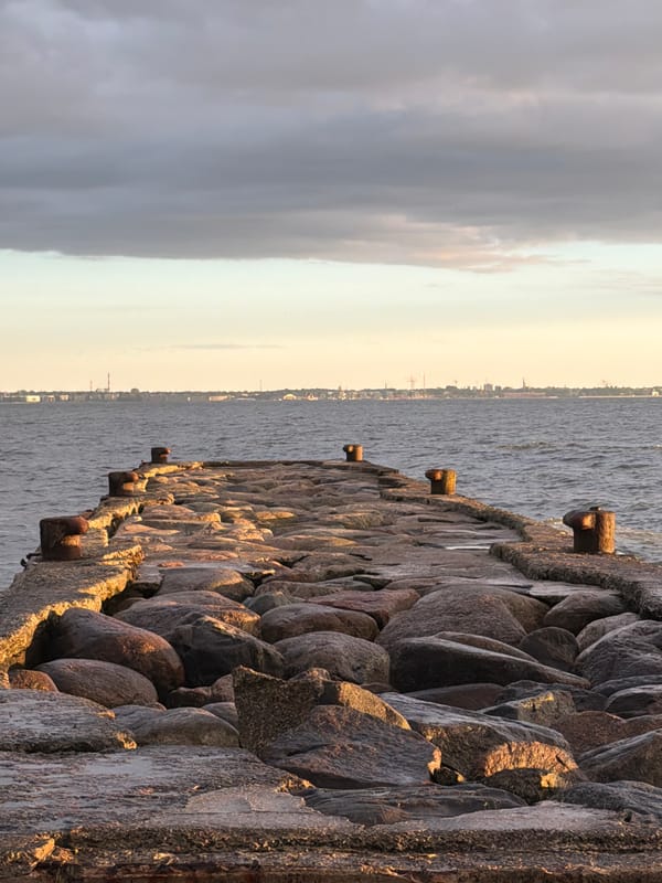 Sunset waves hit Tallinn's rocky shoreline by the pier