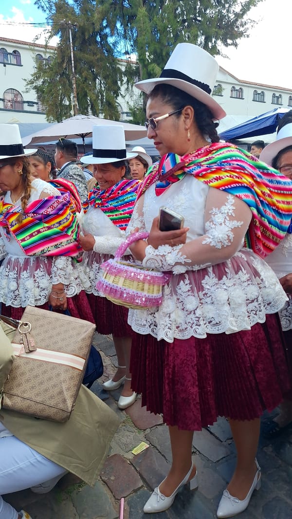 Women in traditional dress gather outdoors in daytime gathering