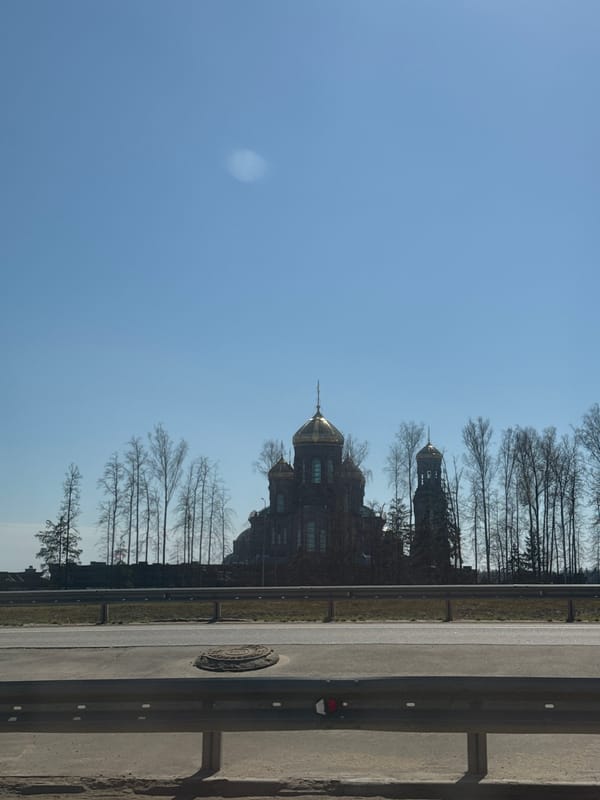 Golden-domed church with bell tower spotted among bare trees