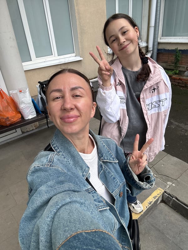 Two females pose for outdoor selfie with peace signs