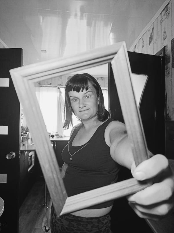 Woman poses with wooden frame in artistic indoor portraits