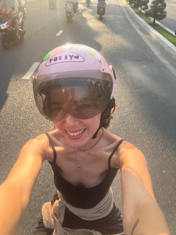 Woman in pink helmet rides motorcycle in Vietnam street