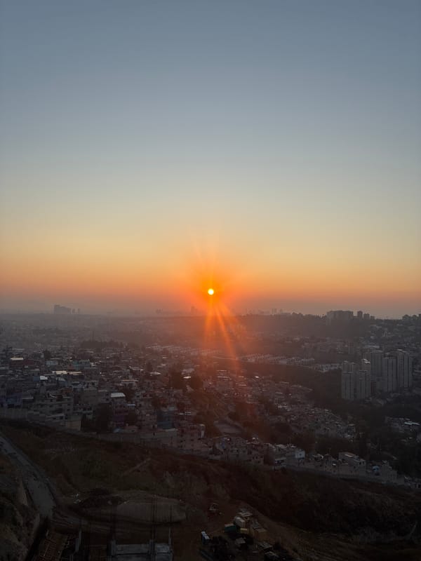 Hazy orange sunset illuminates Huixquilucan de Degollado cityscape