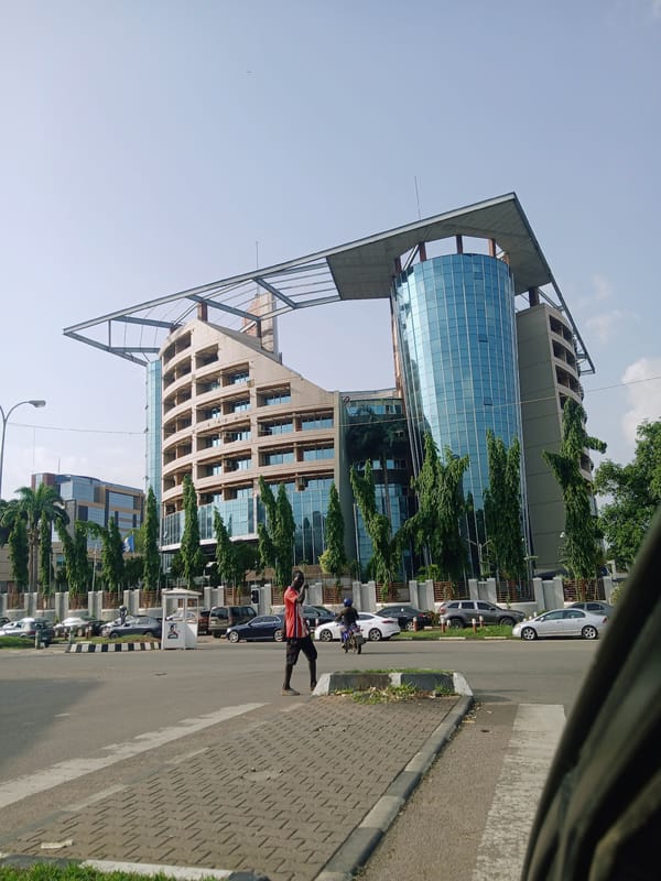 Person walks sidewalk near modern building in Abuja