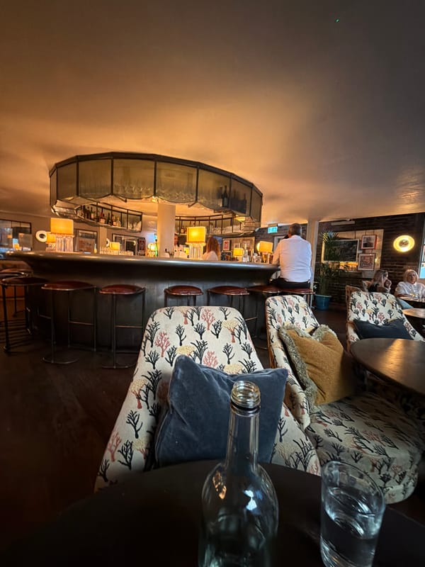 Quiet corner of a dim London bar, drinks on the table