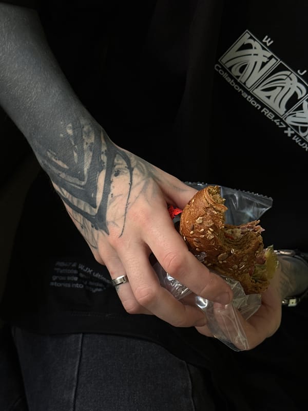 Tattooed person holds half-eaten sandwich in Moscow