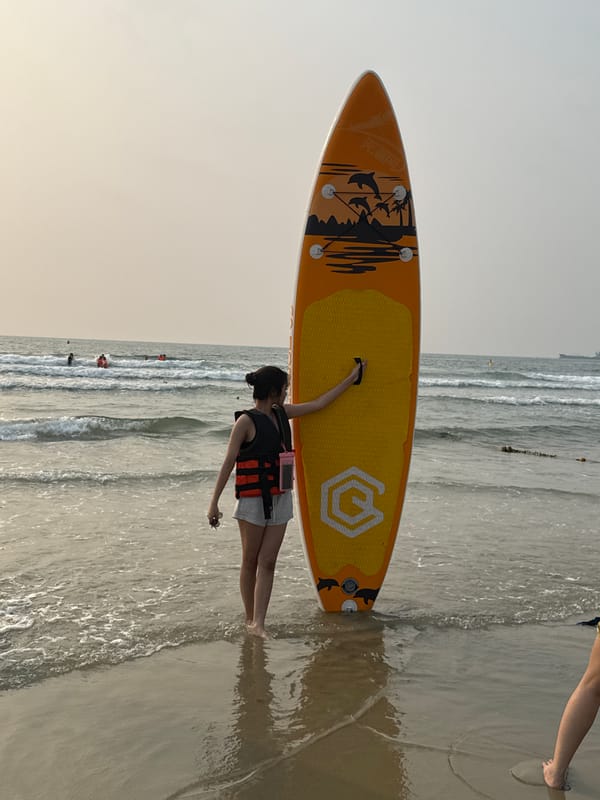 Dawn beach activities: vendors, cleaners, paddleboarder in Đà Nẵng