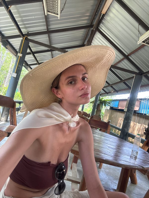 Woman in straw hat photographed at wooden surface