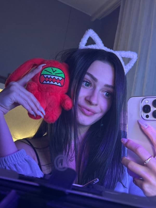 Woman poses for selfie with cat ears and plush toy