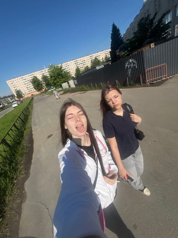 Two women pose for outdoor photo in sunny conditions