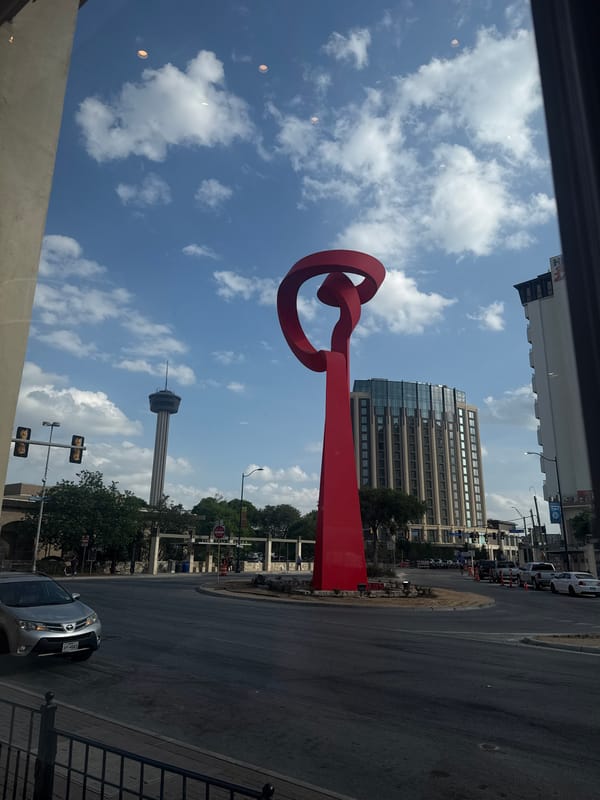 Red abstract sculpture viewed from indoors in San Antonio