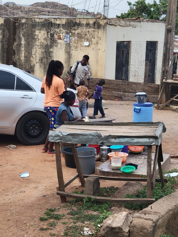 Daily life unfolds around water stand, children play in Jos streets