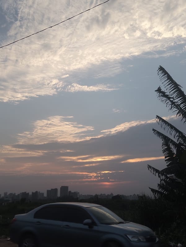 Gray sedan parked in Dhaka lot during sunset