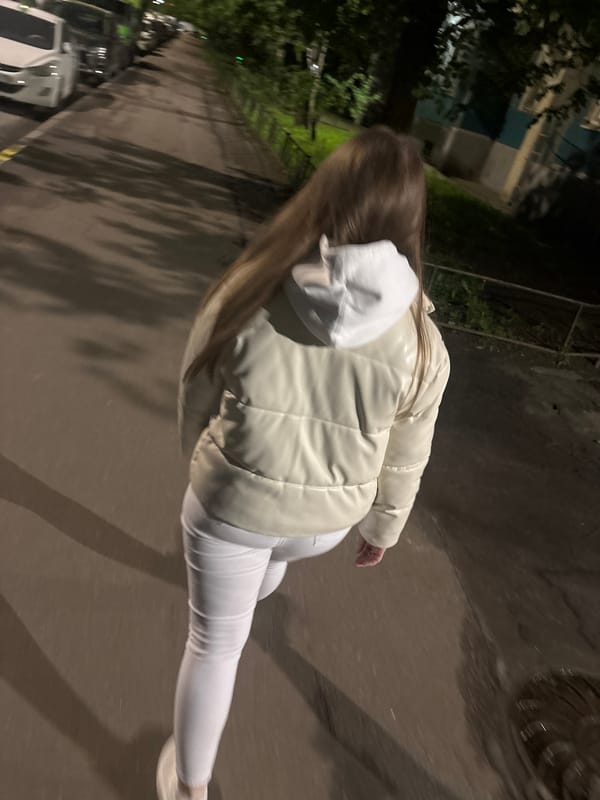 Person in white walks through nighttime city intersection