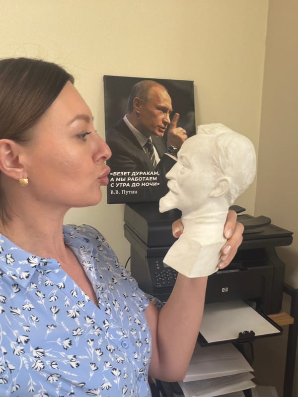 Woman poses with plaster bust near Putin poster in Rostov-on-Don
