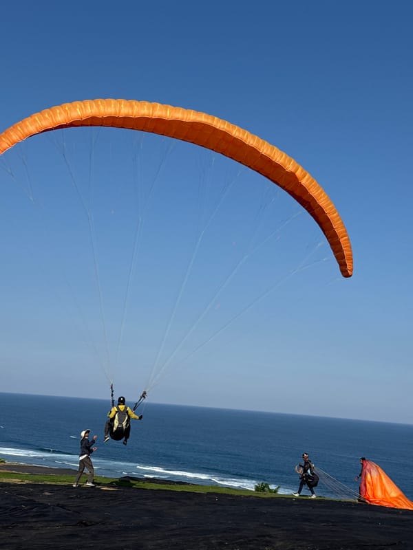 Paragliders soar over Kuta Selatan as tourists capture aerial display