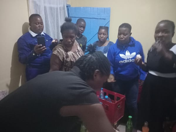Women share meal in small room gathering in Kakamega