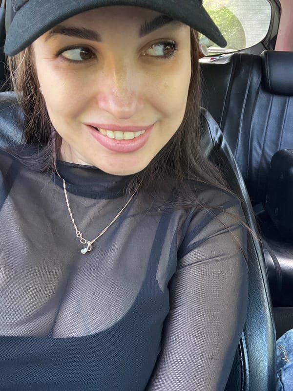 Woman photographed in car wearing black outfit and cap