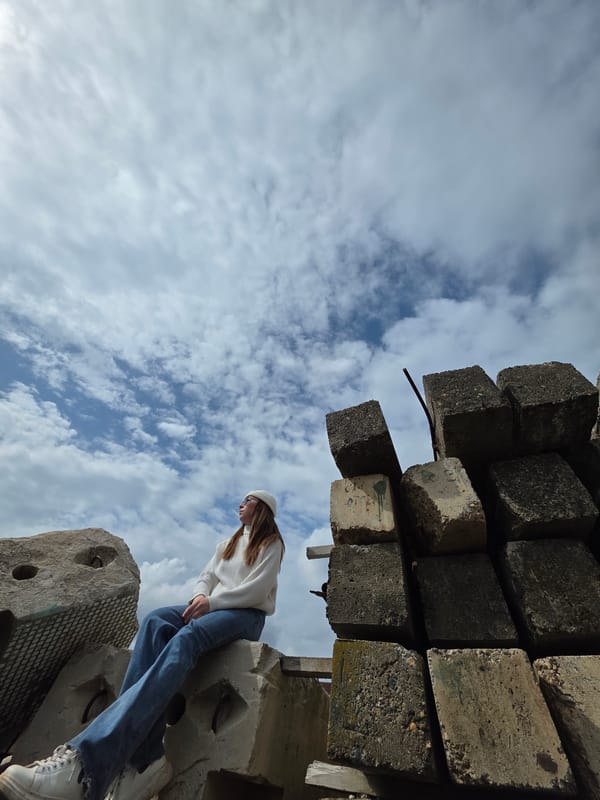 Person sits on concrete blocks in casual outfit