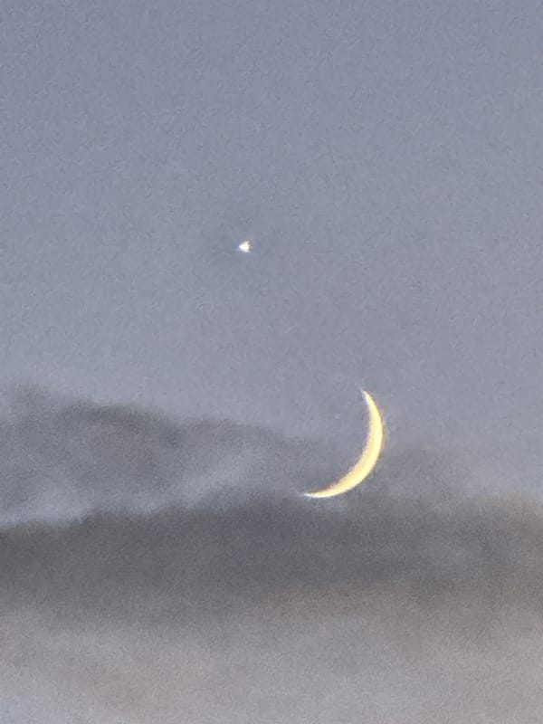 Crescent moon and bright planet at dusk over Bischheim