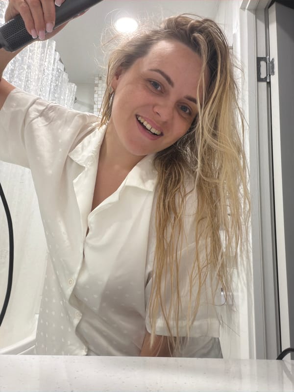 Woman styling hair with Dyson dryer in Votkinsk bathroom
